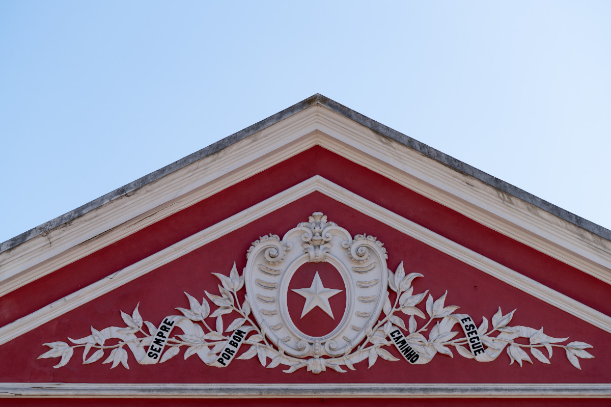 pormenor do topo frontal de um edifício, no Bairro Grandella, onde se lê Sempre por bom caminho e segue