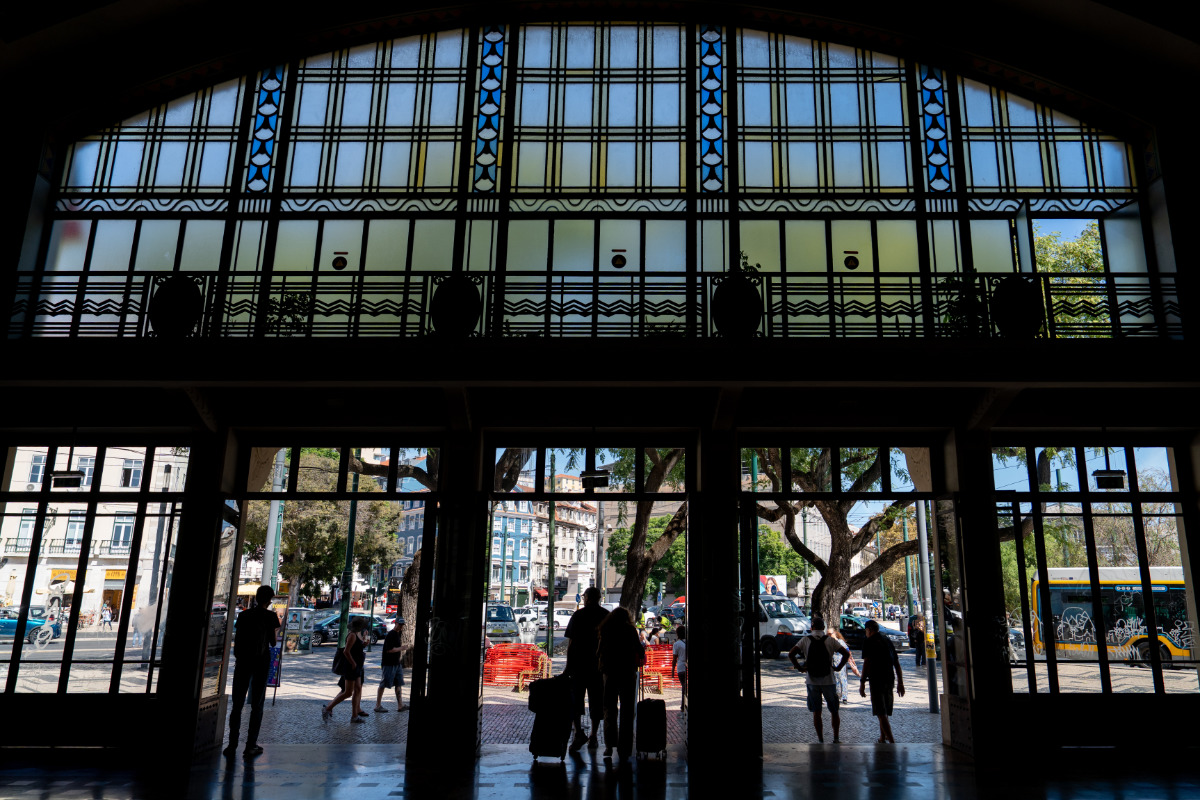 fotografia a partir do interior da estação ferroviária do cais do sodré com o movimento de pessoas a entrar e a sair pela porta principal da estação