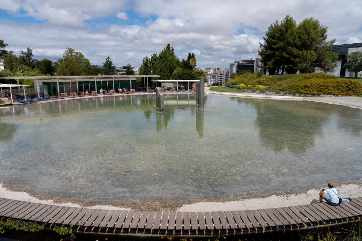 Homem sentado num banco próximo ao lago do Jardim Amália Rodrigues.