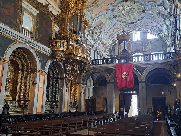 Interior da Igreja de Santa Catarina com decoração barroca, altares dourados, teto ornamentado e cadeiras alinhadas na nave, destacando-se a arquitetura histórica e religiosa.
