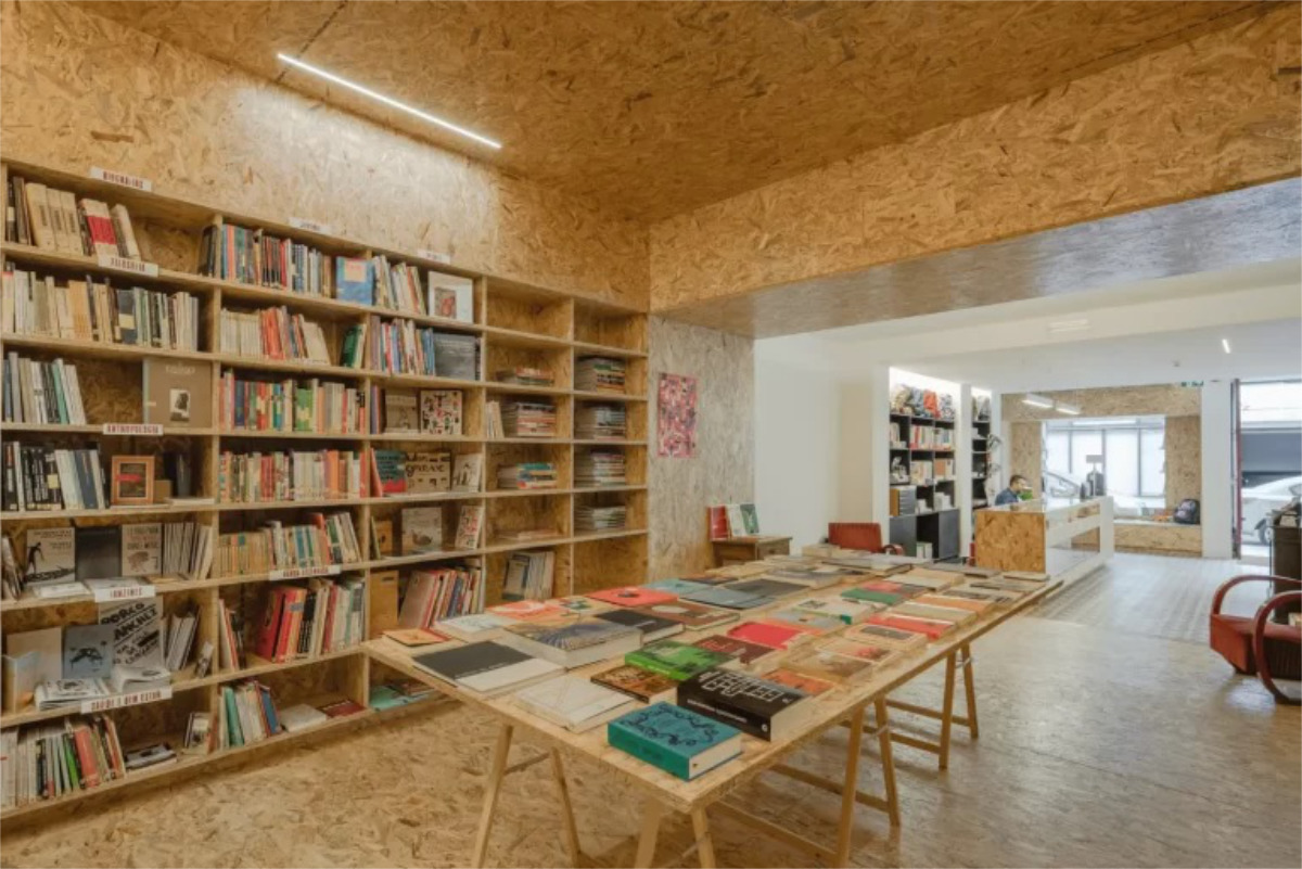 Moderna livraria Tigre de Papel com estantes de livros, mesa de leitura com revistas e espaço confortável para leitura e estudo.