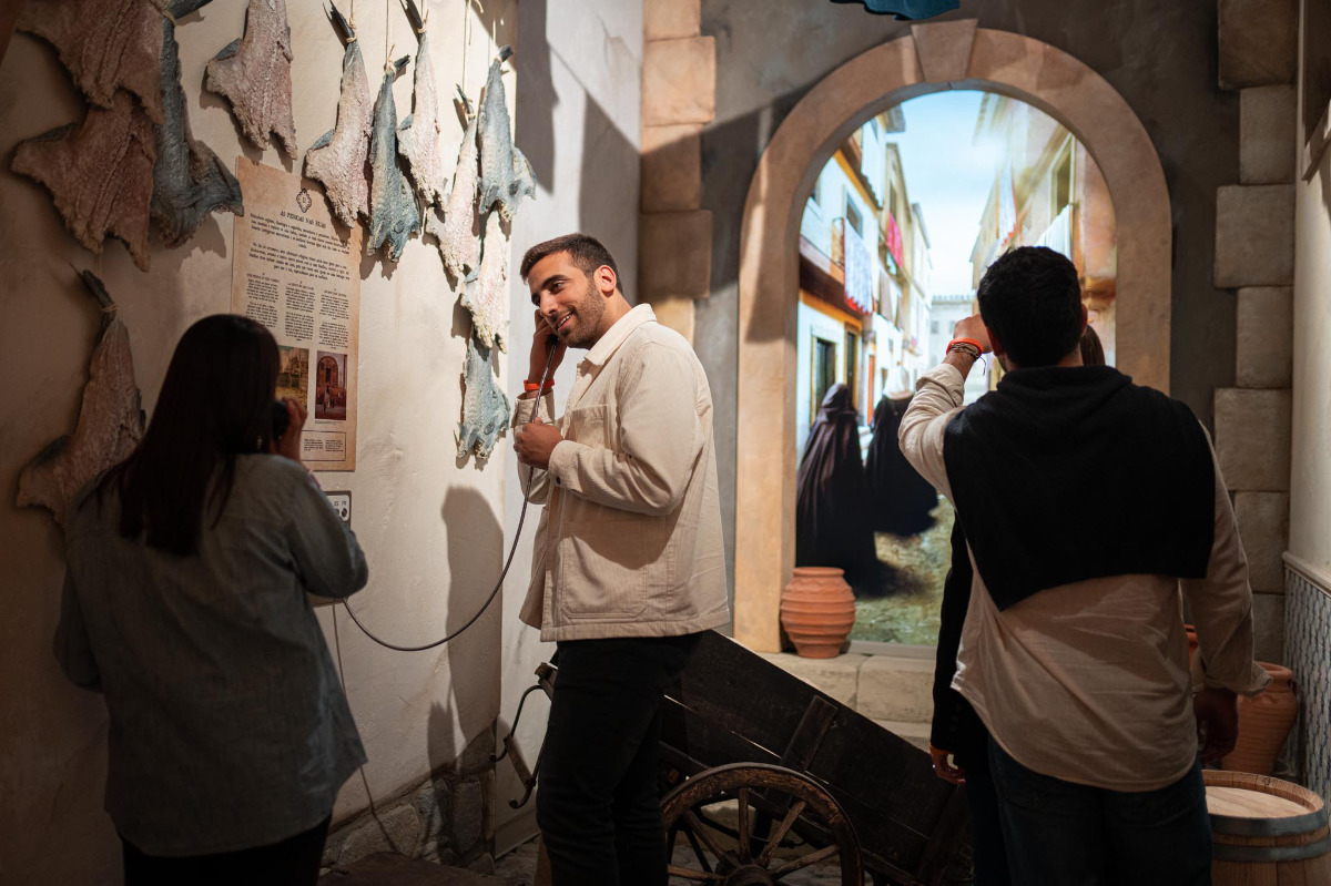 Visitantes a percorrer a área expositiva, recorrem aos equipamentos disponíveis com audiodescrição.