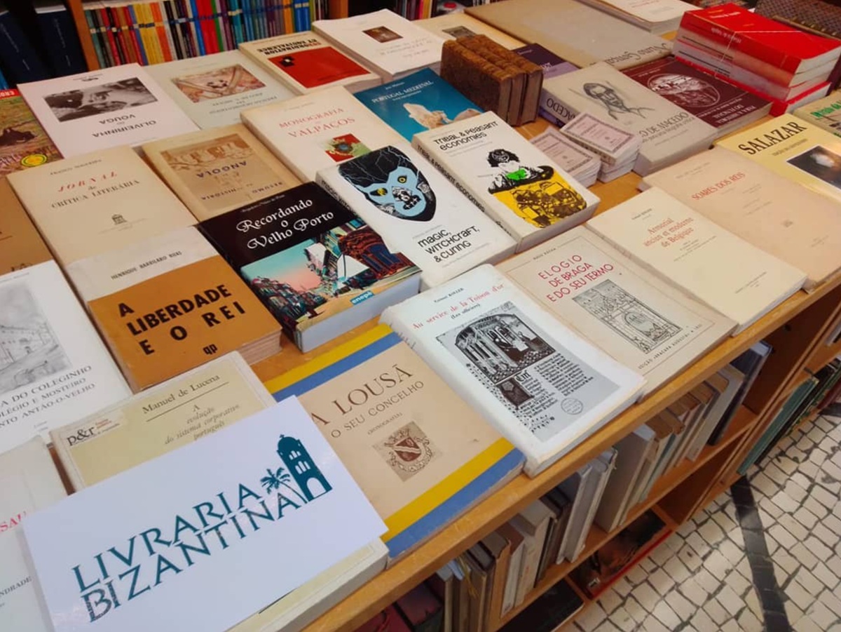 Uma mesa com diversos livros no interior da Livraria Alfarrabista Bizantina