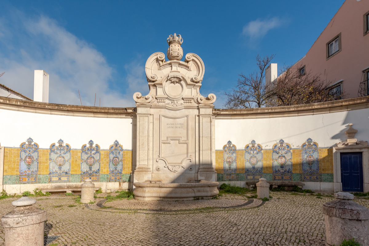 Chafariz da Junqueira ladeado pelos coloridos painéis de azulejo em tons de amarelo e azul