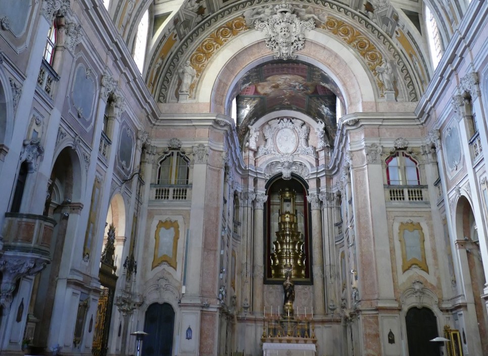 A imagem retrata o interior da Igreja da Encarnação, grandiosa e ornamentada, com decoração barroca elaborada.