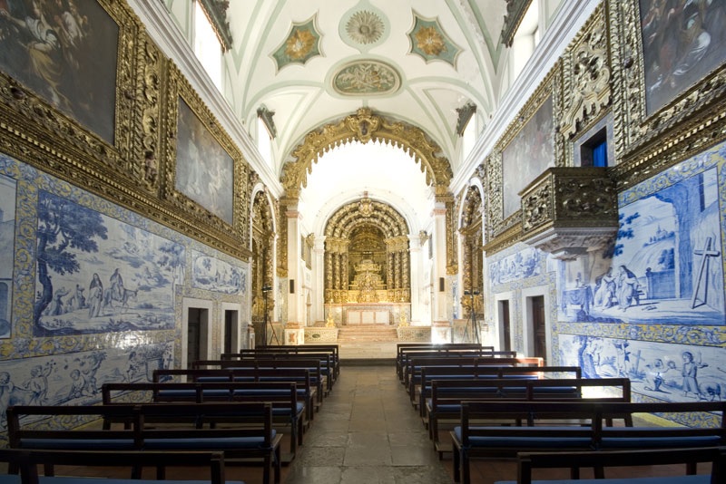 Vista interior da Igreja das Chagas, ricamente decorada, com elaborados detalhes dourados e intrincados desenhos no teto.