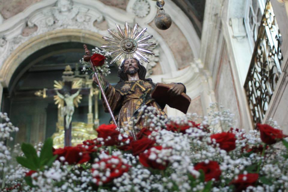 No interior da Igreja de Santiago, destaque da estátua de Santiago, rodeada por flores vermelhas e brancas.