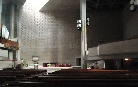 Interior da Igreja do Sagrado Coração de Jesus, moderna, com bancos de madeira, altar simples e iluminação suave.