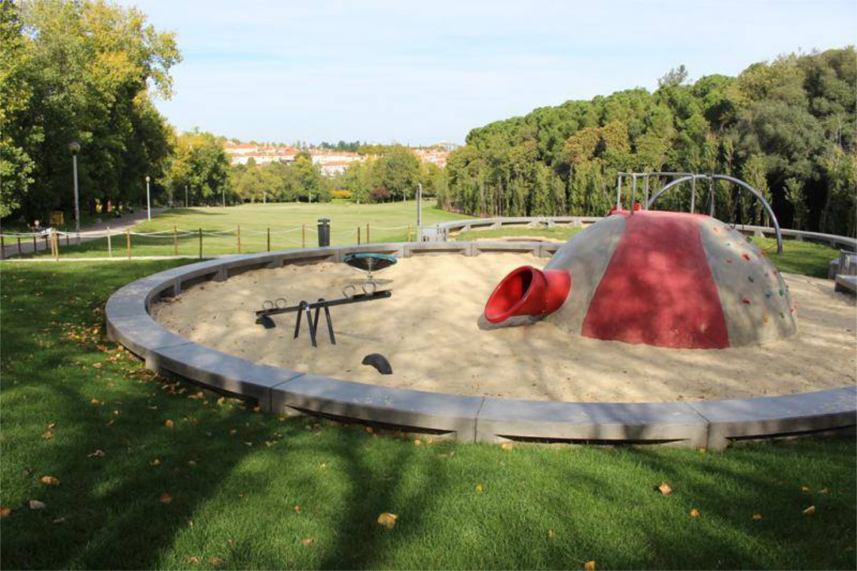 No Parque do Vale do Silêncio, um pequeno parque infantil para crianças com baloiços, cercado por árvores e áreas verdes.